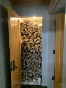 A closet full of wood logs that opens to the indoors and the outdoors. 